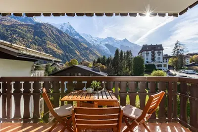 a wooden table and chairs on a balcony with mountains at Savoy Cosy 1CH pied pistes Hypercentre Vue MtBlanc in Chamonix-Mont-Blanc