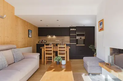 a living room and kitchen with a couch and a table at Savoy Cosy 1CH pied pistes Hypercentre Vue MtBlanc in Chamonix-Mont-Blanc