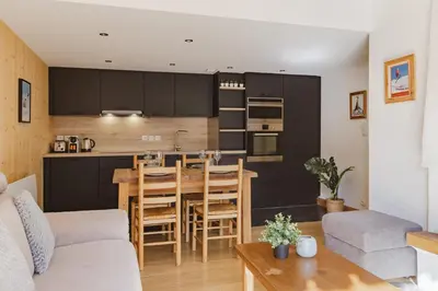 a kitchen and living room with a table and chairs at Savoy Cosy 1CH pied pistes Hypercentre Vue MtBlanc in Chamonix-Mont-Blanc