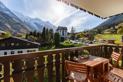 a balcony with a table and chairs and mountains at Savoy Cosy 1CH pied pistes Hypercentre Vue MtBlanc in Chamonix-Mont-Blanc