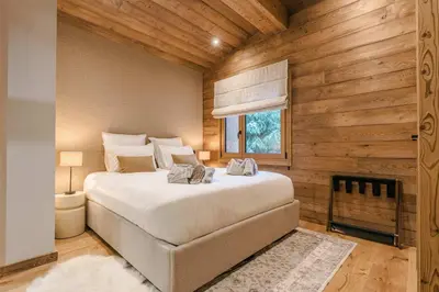 a bedroom with a large bed in a room with wooden walls at Luxury Chalet with Private Spa & Wellness Area in Megève