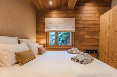 a bedroom with a white bed with a window at Luxury Chalet with Private Spa & Wellness Area in Megève