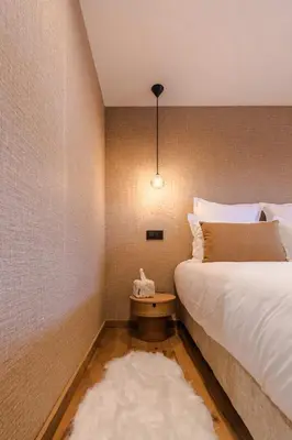 a bedroom with a bed and a night stand with a white rug at Luxury Chalet with Private Spa & Wellness Area in Megève