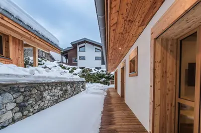 a walkway in the snow next to a stone wall at Luxury Chalet with Private Spa & Wellness Area in Megève