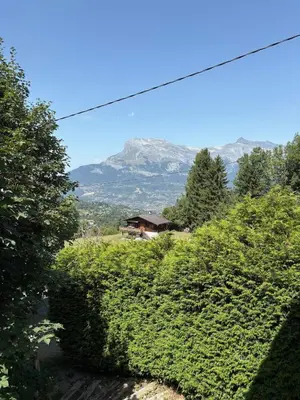 a house on a hill with a mountain in the background at La CHACUNIERE GRAND CHALET ST NICOLAS DE VEROCE, PRES DES PISTES in La Chapelle