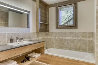a bathroom with a tub and a sink and a mirror at Chalet exceptionnel de 600m2 - Spa, salle de gym, ski-room in Samoëns
