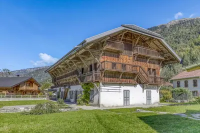 a large house with a wooden roof at Chalet exceptionnel de 600m2 - Spa, salle de gym, ski-room in Samoëns