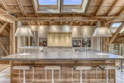 a large kitchen with a large counter with stools at Chalet exceptionnel de 600m2 - Spa, salle de gym, ski-room in Samoëns