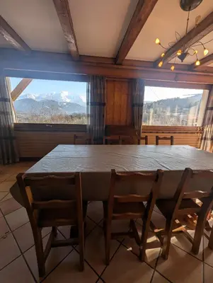 a dining room with a table and a large window at Chez Math et Lolo in Sallanches