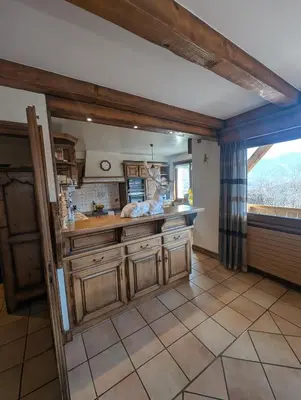 a kitchen with wooden cabinets and a large window at Chez Math et Lolo in Sallanches
