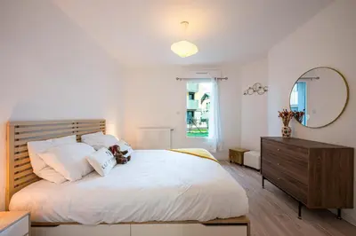 a white bedroom with a large bed and a mirror at Capucines des Alpes - Au pied du Mont Blanc in Saint-Gervais-les-Bains