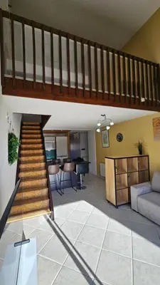 a staircase in a living room with a couch and a table at Ecrin du Mont-Blanc - Duplex Panoramique in Sallanches