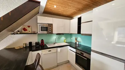 a kitchen with white cabinets and black counter tops at Ecrin du Mont-Blanc - Duplex Panoramique in Sallanches