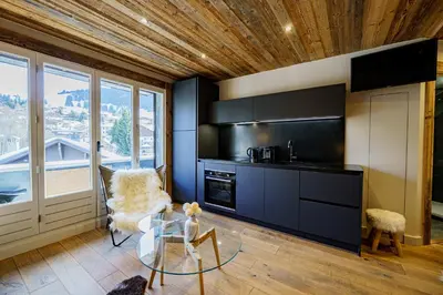 a kitchen with black cabinets and a glass table at Alpine Mood - Proche des pistes et Centre ville in Megève