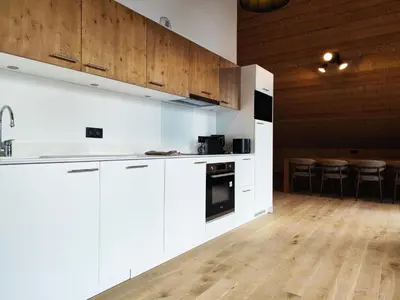 a kitchen with white cabinets and a wooden floor at La Source in Saint-Gervais-les-Bains
