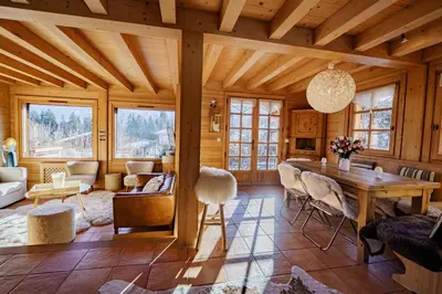 a living room with a wooden ceiling and a table at Chalet Panorama in Combloux