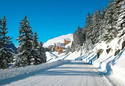 a road covered in snow with a ski lodge on a mountain at Pied des pistes, piscine, jacuzzi in Flaine