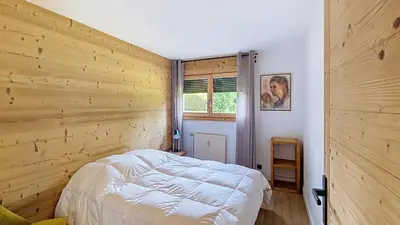 a bedroom with a wooden wall with a bed in it at 1 Riante Colline Arnica - PROCHE CENTRE in Megève