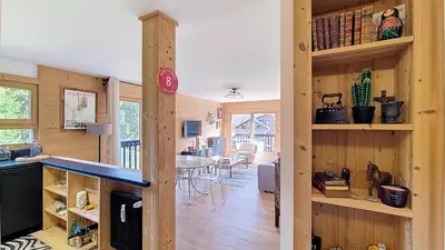 a kitchen and dining room with wooden walls and wooden floors at 1 Riante Colline Arnica - PROCHE CENTRE in Megève