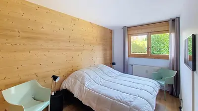 a bedroom with a bed and two chairs in it at 1 Riante Colline Arnica - PROCHE CENTRE in Megève