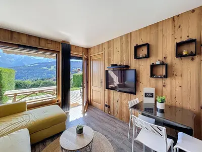 a living room with a couch and a television and a table at Appartement 2 pièces avec coin montagne, parking, vue Mont Blanc - FR-1-560-167 in Combloux