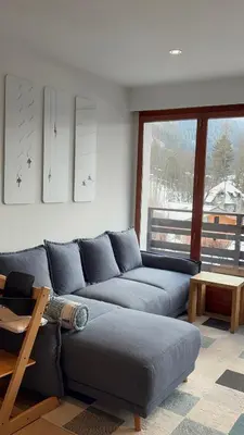 a living room with a blue couch and a table at Appartement familial cosy proche centre in Chamonix-Mont-Blanc