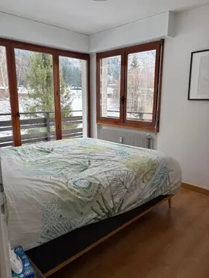 a bedroom with a bed in a room with windows at Appartement familial cosy proche centre in Chamonix-Mont-Blanc