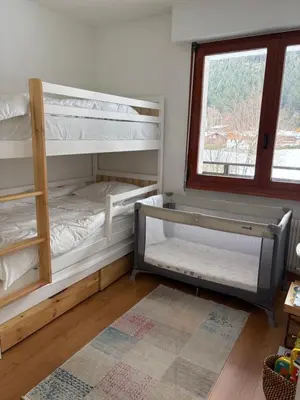 two bunk beds in a room with a window at Appartement familial cosy proche centre in Chamonix-Mont-Blanc