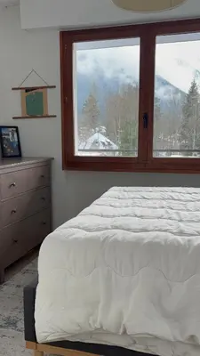 a bedroom with a bed and a large window at Appartement familial cosy proche centre in Chamonix-Mont-Blanc