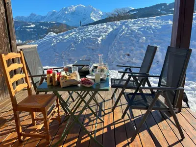 a table with food and two chairs on a porch at Terrasse du MtBlanc in Combloux