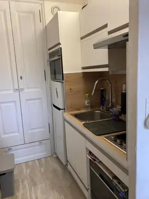 a small kitchen with white cabinets and a sink at Terrasse du MtBlanc in Combloux