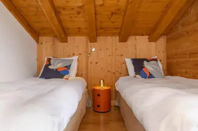 two twin beds in a room with wooden walls at Folettes Chalet 4CH Jardin Vue Cheminee Jacuzzi in Chamonix-Mont-Blanc