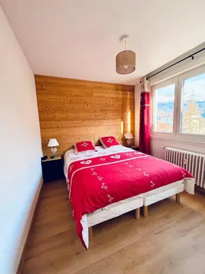 a bedroom with a red bed with a wooden wall at L'écrin des quatre horizons in Saint-Gervais-les-Bains