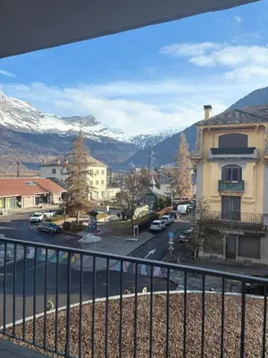 a view from a balcony of a town with snow covered mountains at L'écrin des quatre horizons in Saint-Gervais-les-Bains