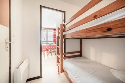 a bedroom with two bunk beds and a dining room at Appartement au pied des pistes - Vue imprenable in Samoëns