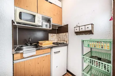 a small kitchen with a microwave and a sink at Appartement au pied des pistes - Vue imprenable in Samoëns