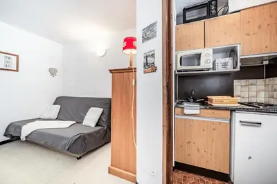a small kitchen with a bed and a microwave at Appartement au pied des pistes - Vue imprenable in Samoëns