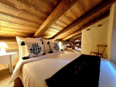 a large bed in a room with a wooden ceiling at A Soulful Alpine Retreat in Megève in Megève