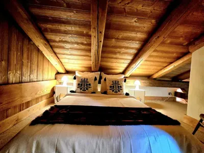 a bedroom with a large bed in a wooden ceiling at A Soulful Alpine Retreat in Megève in Megève