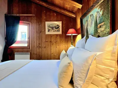 a bedroom with a bed with white pillows and a window at A Soulful Alpine Retreat in Megève in Megève