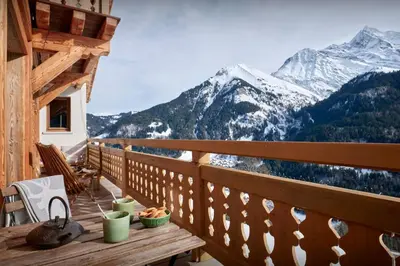 a wooden balcony with a table with a view of mountains at Chalet Lauda - OVO Network in Saint-Nicolas-de-Véroce