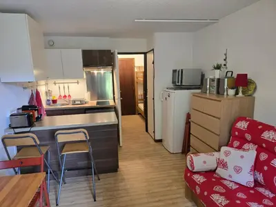 a small kitchen and living room with a red couch at Studio à 2 mn à pied des pistes de Mégève in Demi-Quartier