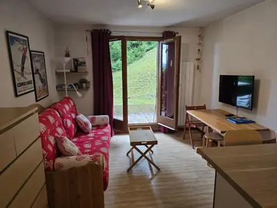 a living room with a red couch and a table at Studio à 2 mn à pied des pistes de Mégève in Demi-Quartier