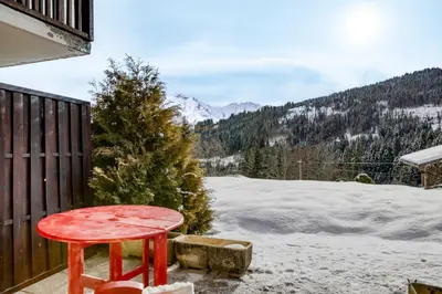 a red stool sitting on a porch in the snow at Appartement F&F in Cordon
