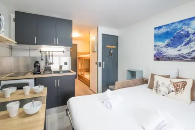 a bedroom with a white bed and a kitchen at Studio L'étoile des neiges - Welkeys in Demi-Quartier