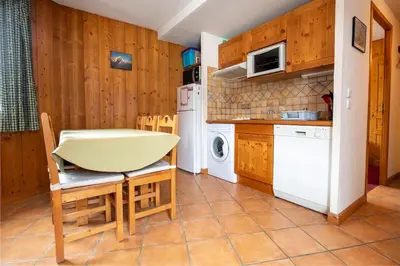 a kitchen with a table and chairs and a white appliance at 2 bedroom, balcony and parking near Bellevue lift in Les Houches