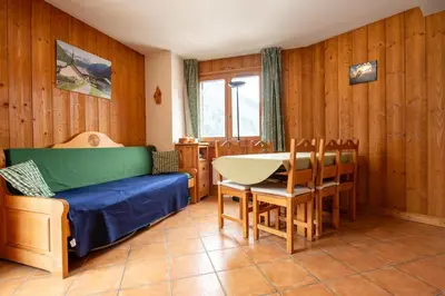 a room with a bed and a table and chairs at 2 bedroom, balcony and parking near Bellevue lift in Les Houches