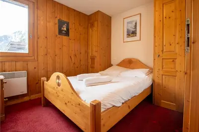 a bedroom with a bed with wooden walls and a window at 2 bedroom, balcony and parking near Bellevue lift in Les Houches