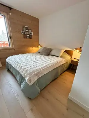 a bedroom with a bed with a wooden wall at Renovated Flat At The Ski Bus Stop In Les Carroz in Arâches-la-Frasse