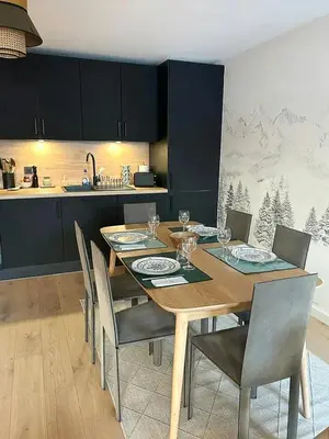a dining room table with chairs and a kitchen at Renovated Flat At The Ski Bus Stop In Les Carroz in Arâches-la-Frasse